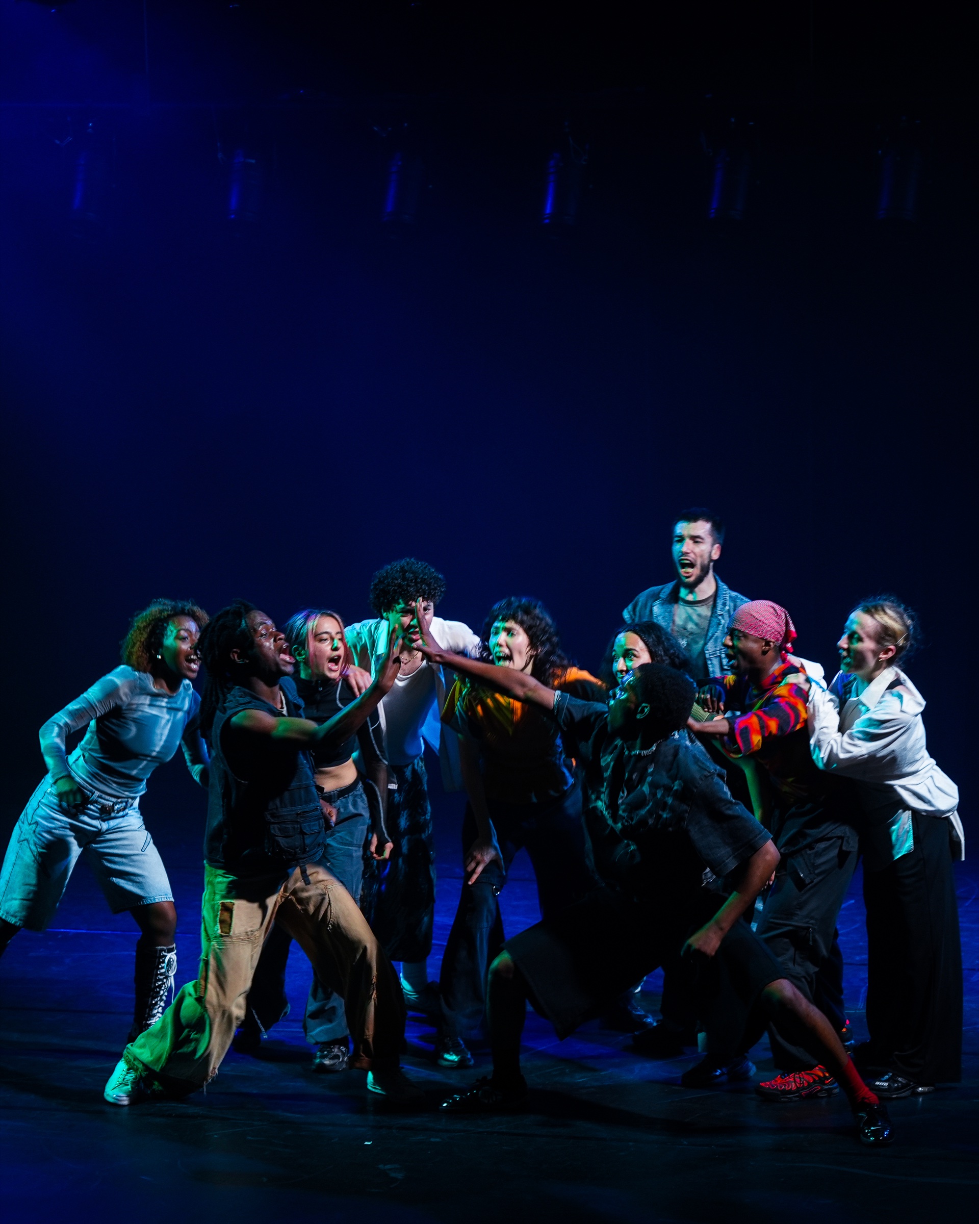 Troupe de danse réunie sur une scène éclairée en bleu